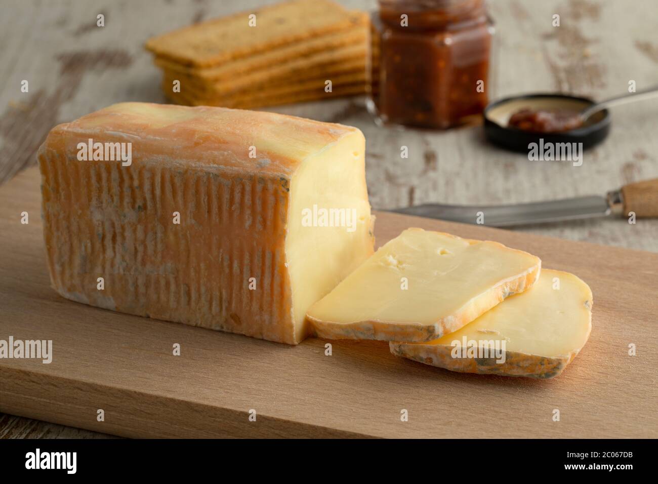 Piece and slices of traditional Italian Taleggio dop cheese close up on a cutting board Stock Photo
