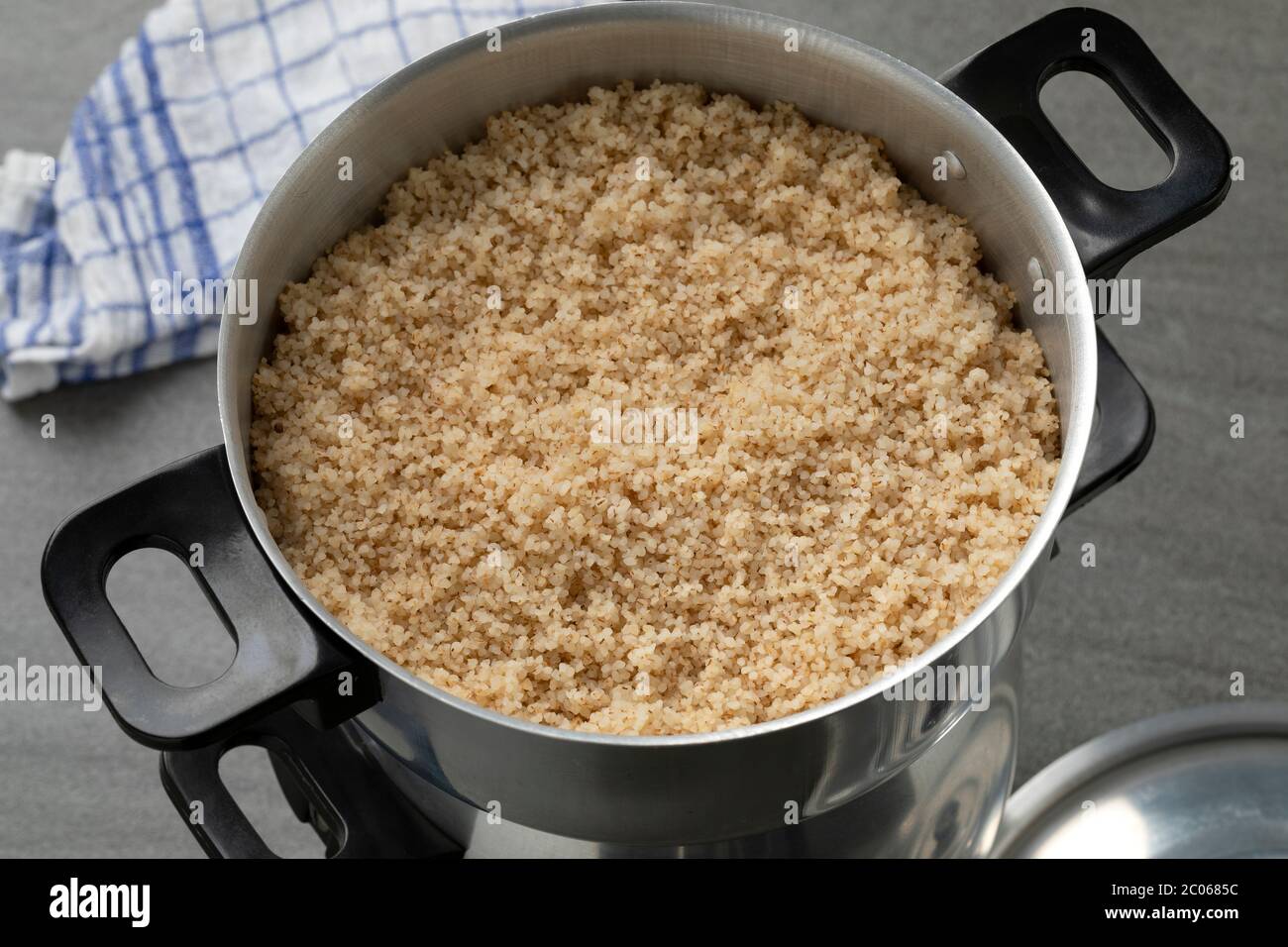Steamed barley grits, belboula, in a traditional aluminum food steamer close up Stock Photo