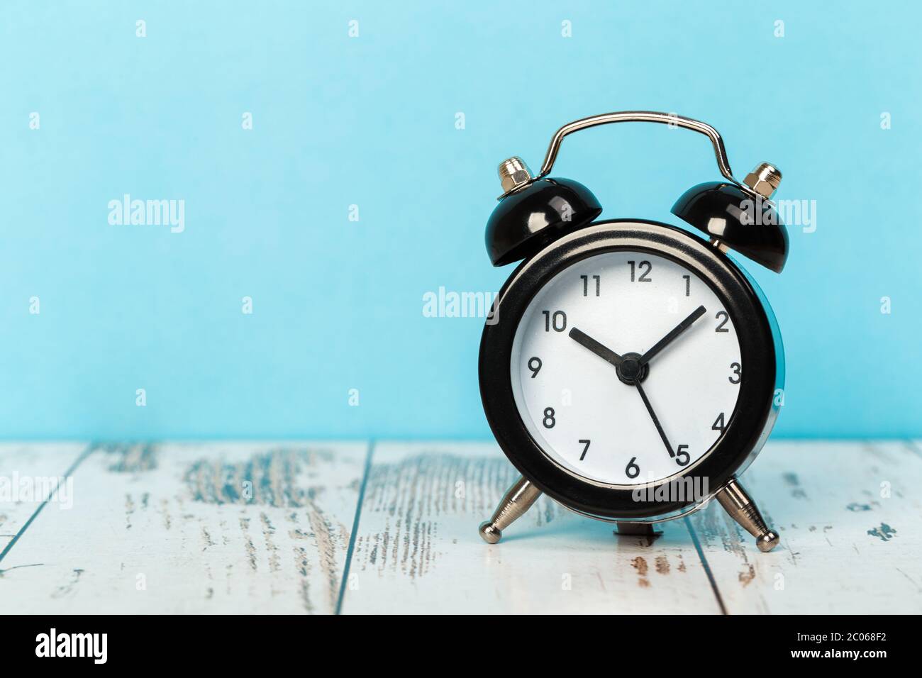 Black retro alarm clock with bells on a wooden table, daily routine