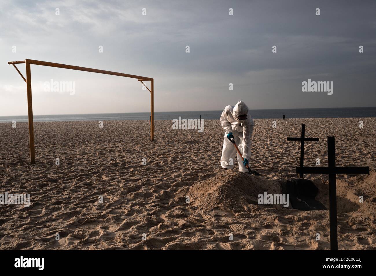Rio De Janeiro, Brazil. 11th June, 2020. An activist of the NGO Rio de Paz in a protective suit digs graves on Copacabana beach to symbolize the Corona victims in a protest against the government's handling of the crisis. Brazil is the most affected country in Latin America by the corona virus pandemic. Credit: Ian Cheibub/dpa/Alamy Live News Stock Photo