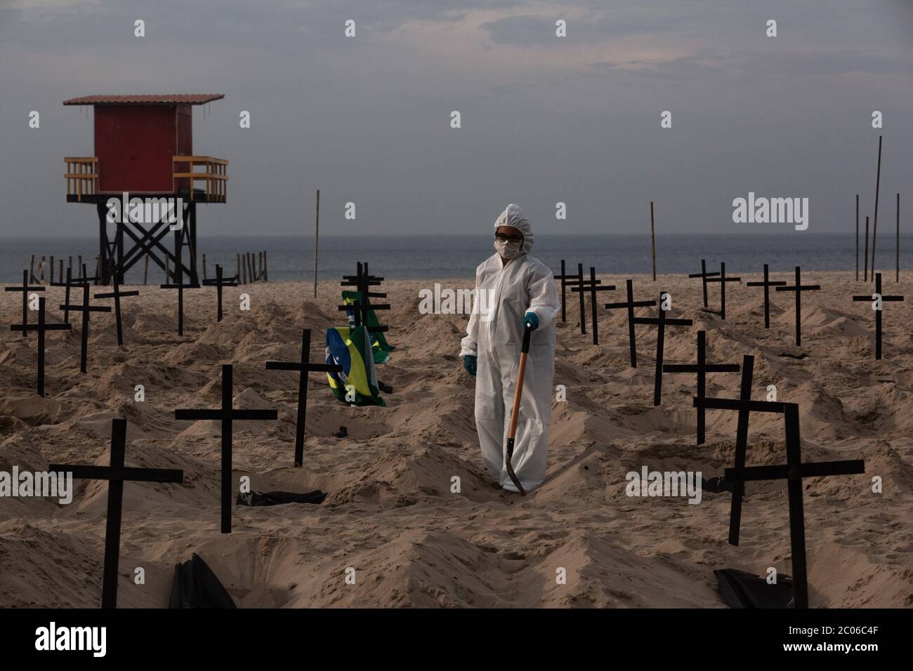 Rio De Janeiro, Brazil. 11th June, 2020. An activist of the NGO Rio de Paz in a protective suit digs graves on Copacabana beach to symbolize the Corona victims in a protest against the government's handling of the crisis. Brazil is the most affected country in Latin America by the corona virus pandemic. Credit: Ian Cheibub/dpa/Alamy Live News Stock Photo