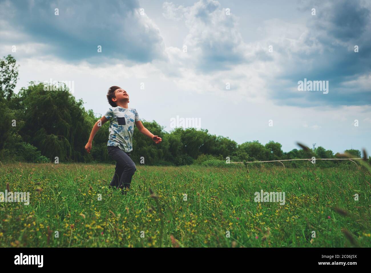 Happy kid looking up to stormy summer sky. Stock Photo