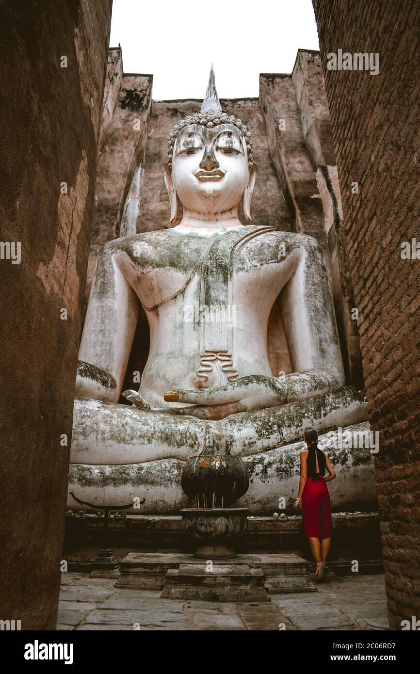 Attractive tourist girl standing in front of the Big Buddha Statue at the Wat Si Chum Temple in Sukhotai Thailand Stock Photo