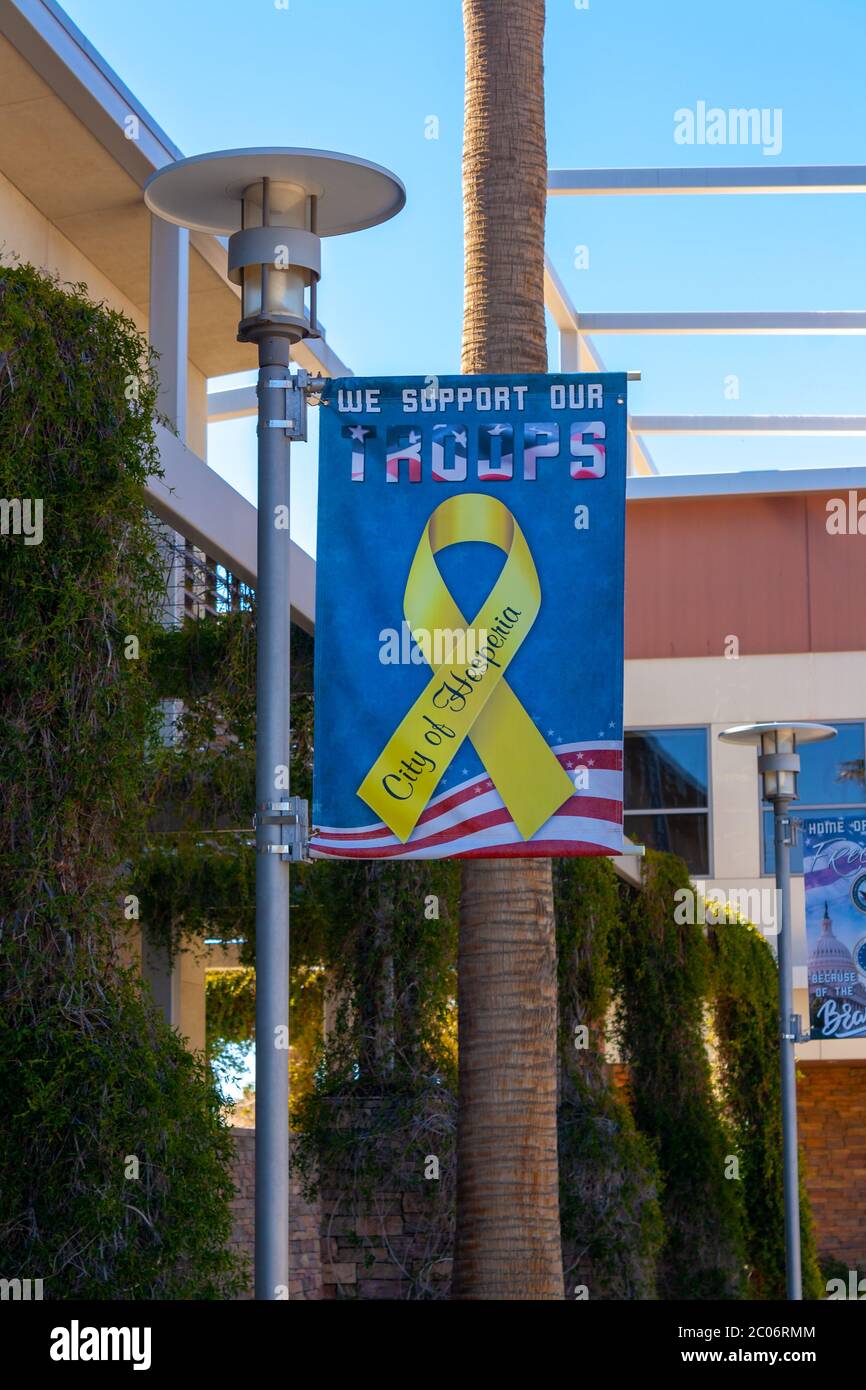 Hesperia, CA / USA - March 13 2019: In Hesperia, California, a “We Support Our Troops” banner hangs on a post at their city hall’s office building. Stock Photo