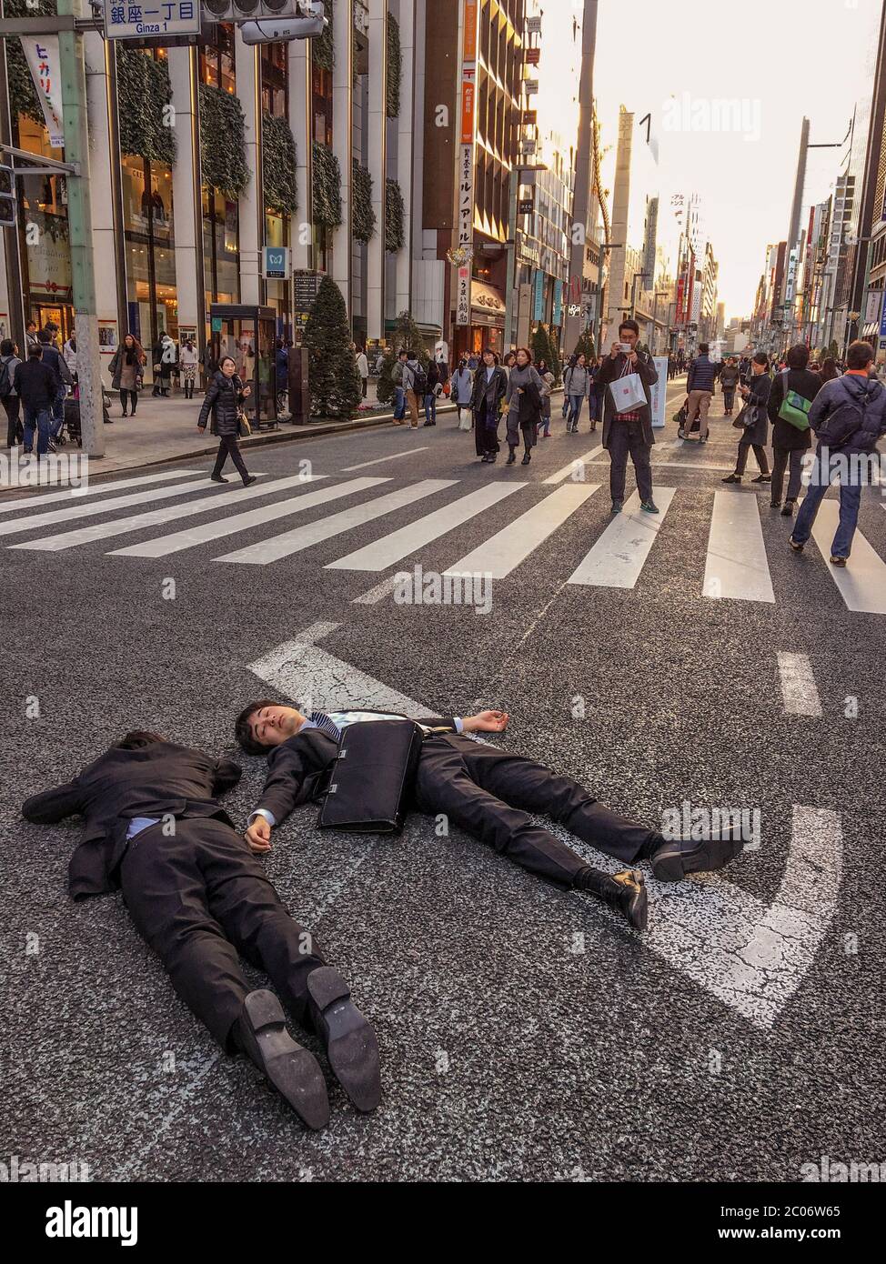 Two Men in Business Suits Lying on a Road at Ginza Tokyo Stock Photo