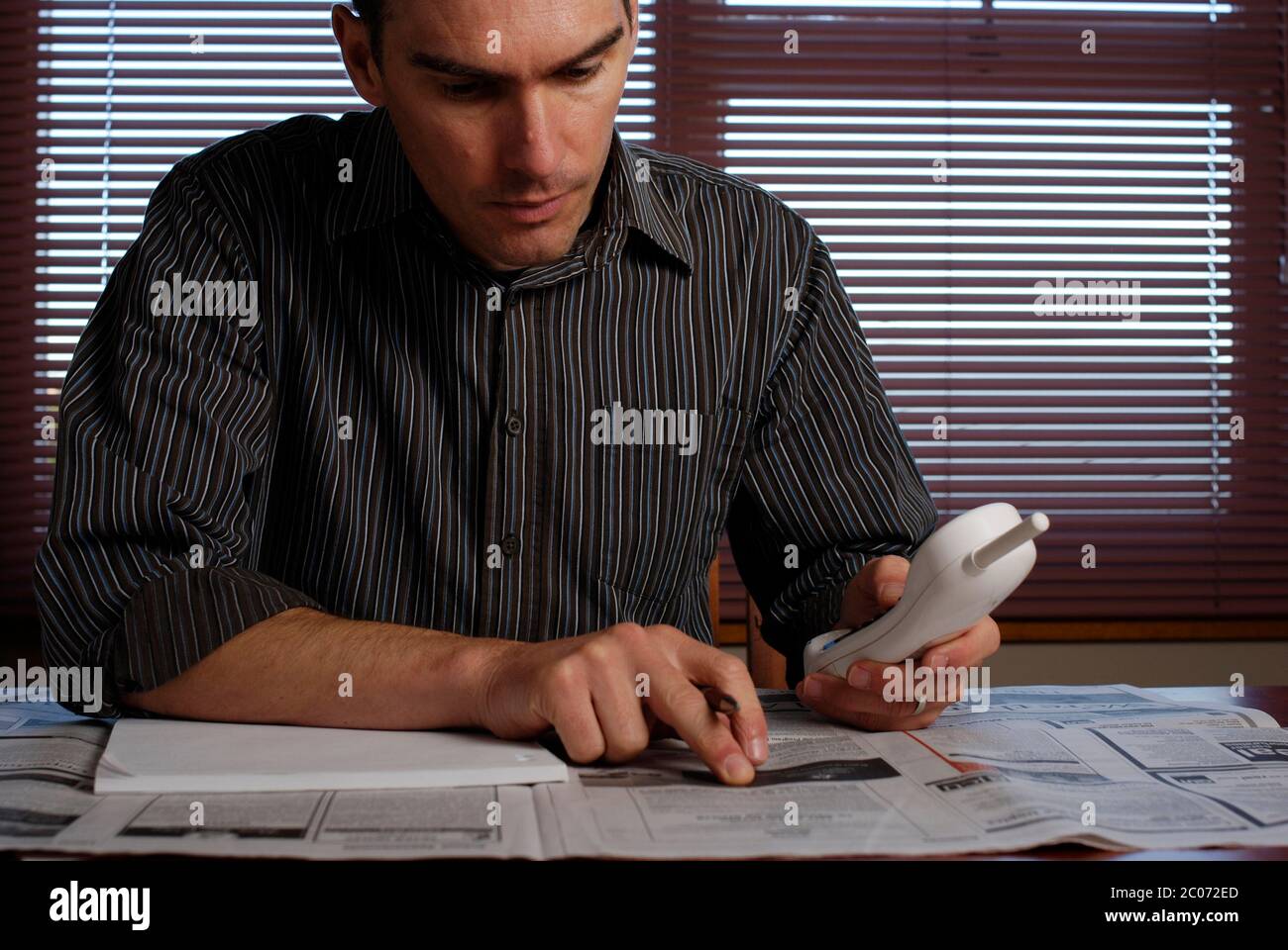 Young man with employment section of newspaper. Stock Photo