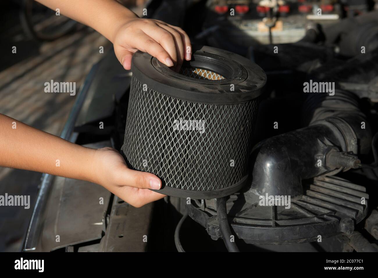 Auto mechanic holding a dirty, air filter over a car engine for cleaning Stock Photo Alamy