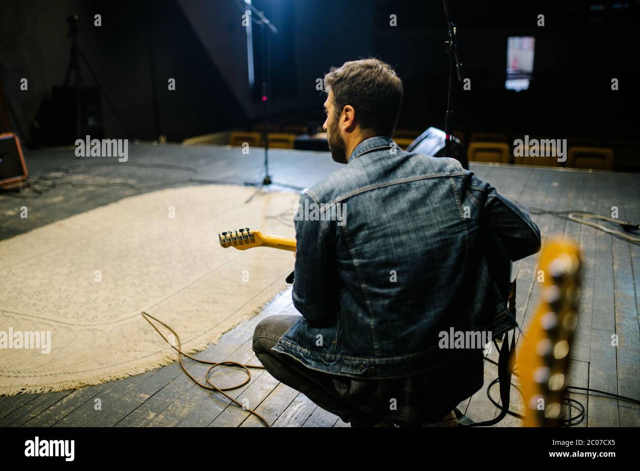 Back view of young guitarist on stage. Soundcheck concept. Stock Photo