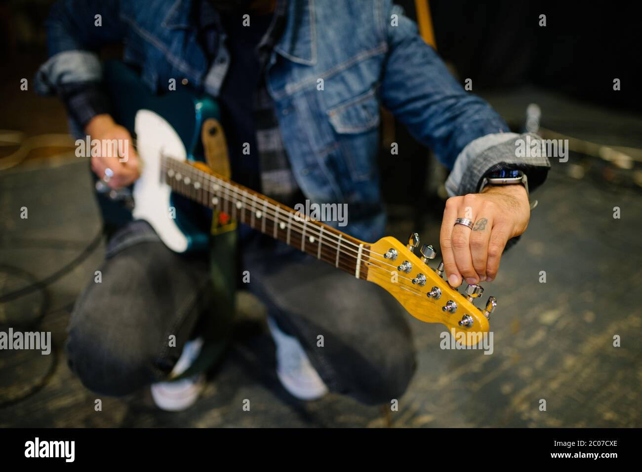 Young guitarist tuning his guitar closeup. Stock Photo