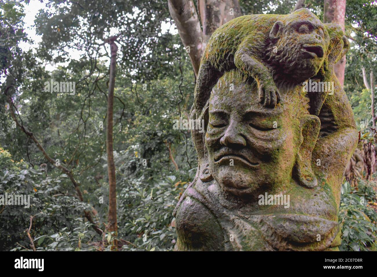 Statue of a monkey sitting on a human head covered by moss in the Sacret Monkey Forest in Ubud Bali Indonesia Stock Photo