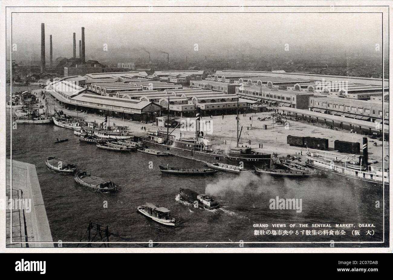 [ 1930s Japan - Central Wholesale Market ] — A panoramic view of the Osaka Central Wholesale Market in Osaka, which played a major role in establishing a stable food market in Osaka and surroundings.  It was opened in Osaka’s Fukushima Ward in November 1931 in response to the violent Rice Riots (米騒動) of 1918. The market was closed during WWII, but reopened in 1950.  20th century vintage postcard. Stock Photo