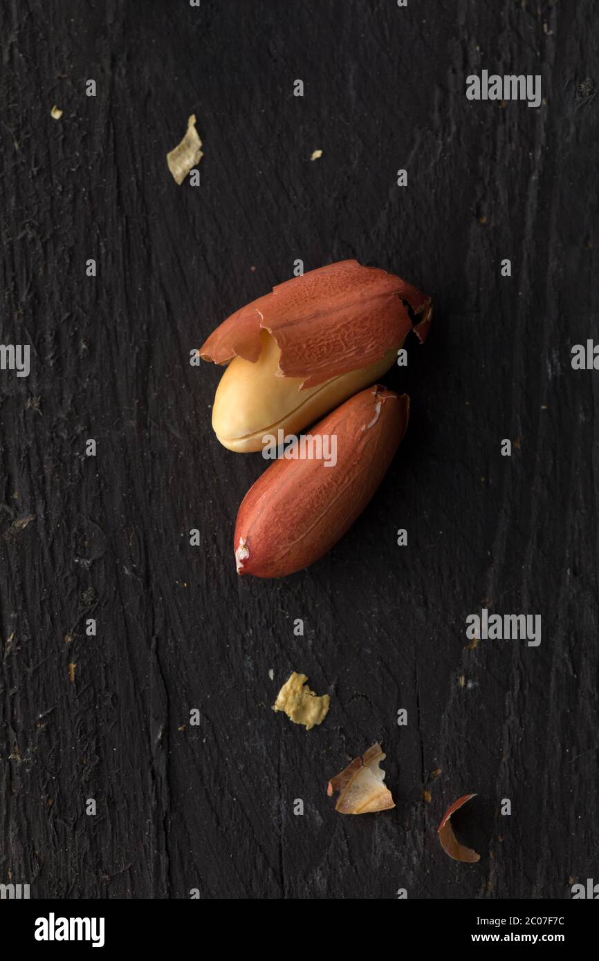 Two Peanuts on Black Wooden Surface Stock Photo