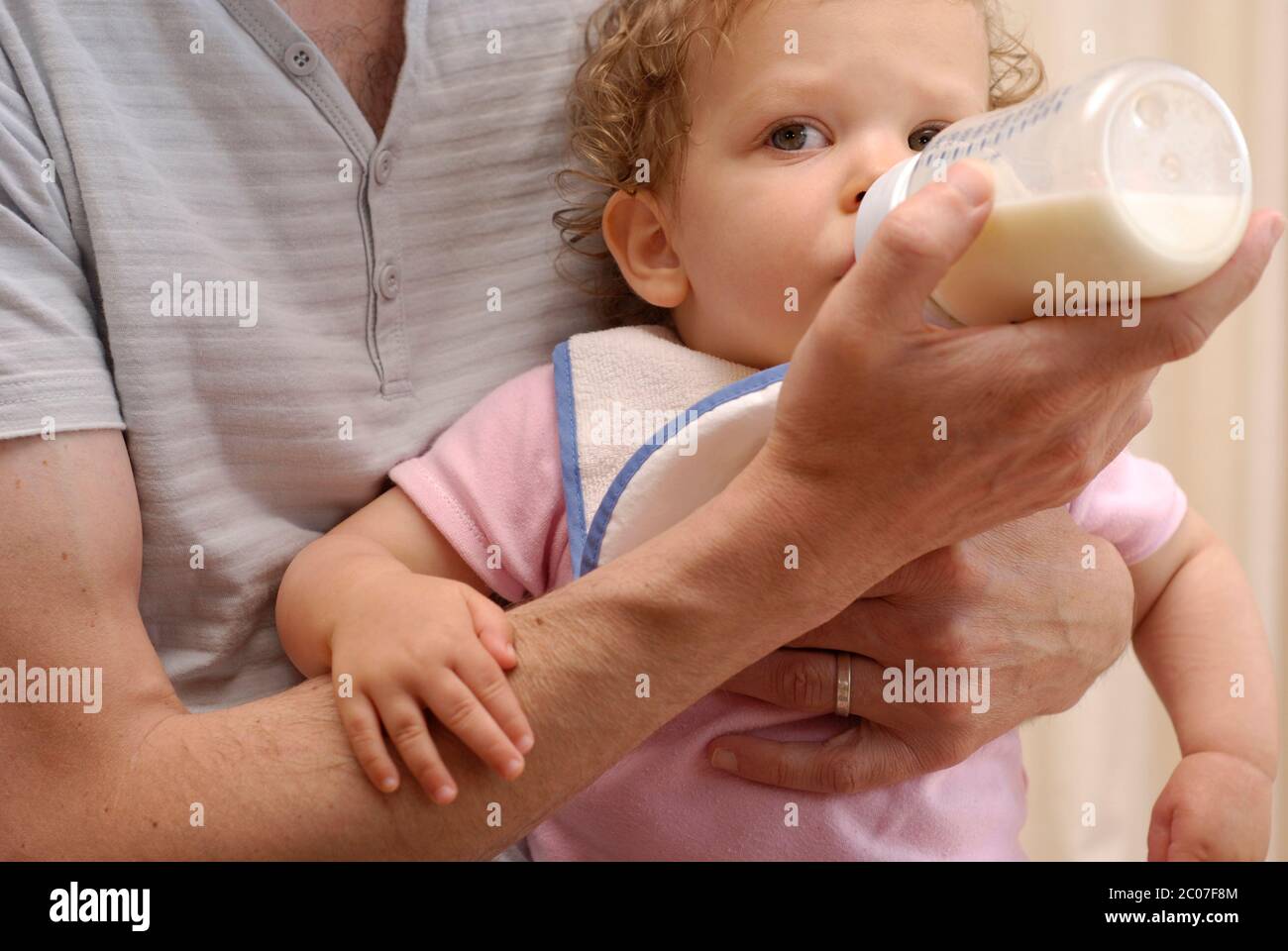 Father feeding his sixteen month old daughter a bottle of milk. Stock Photo