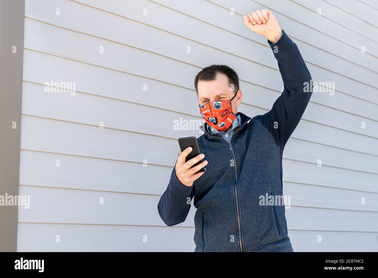 Edmonton, AB, Canada - June 8, 2020: Edmonton Oilers Fan is wearing theme protective cotton mask with Edmonton Oilers logo and cheering for the NHL te Stock Photo