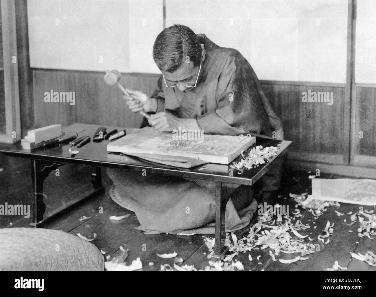 [ 1910s Japan - Japanese Woodblock Artist ] — A Japanese artists is using a hammer and chisel to carve a woodblock for ukiyoe printing.  20th century vintage gelatin silver print. Stock Photo