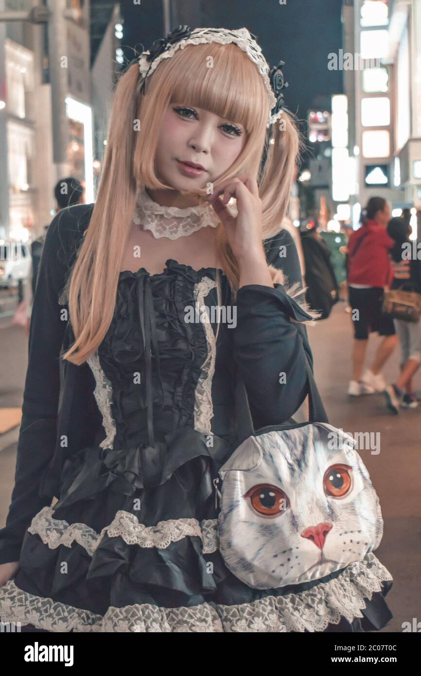 Unidentified Japanese girl in black costume and blonde dived hair with a cat-like hand bag at Harajuku in Tokyo Japan (example of typical Japanese cos Stock Photo