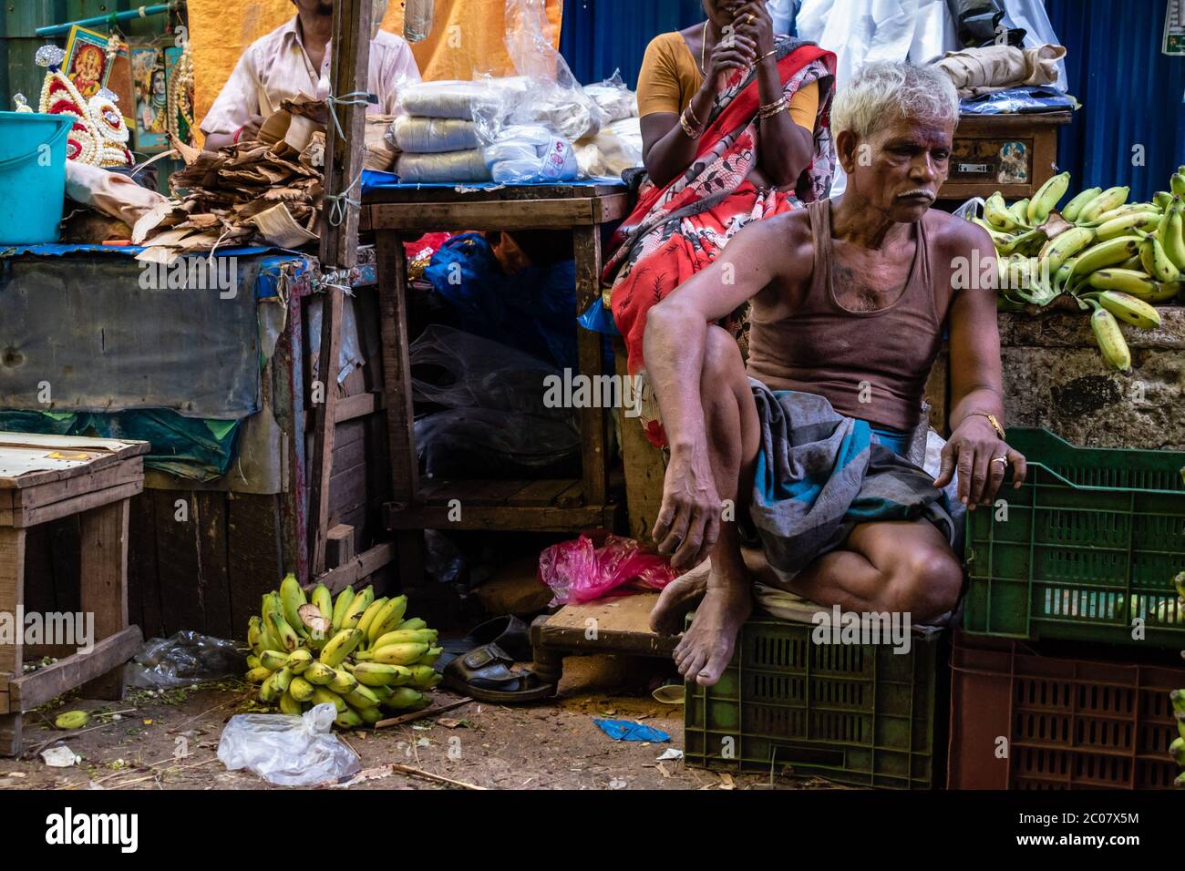 Chennai, Tamil Nadu, India - August 2018: An elderly Indian man sitting in a market wearing an undershirt and staring thoughtfully. Stock Photo