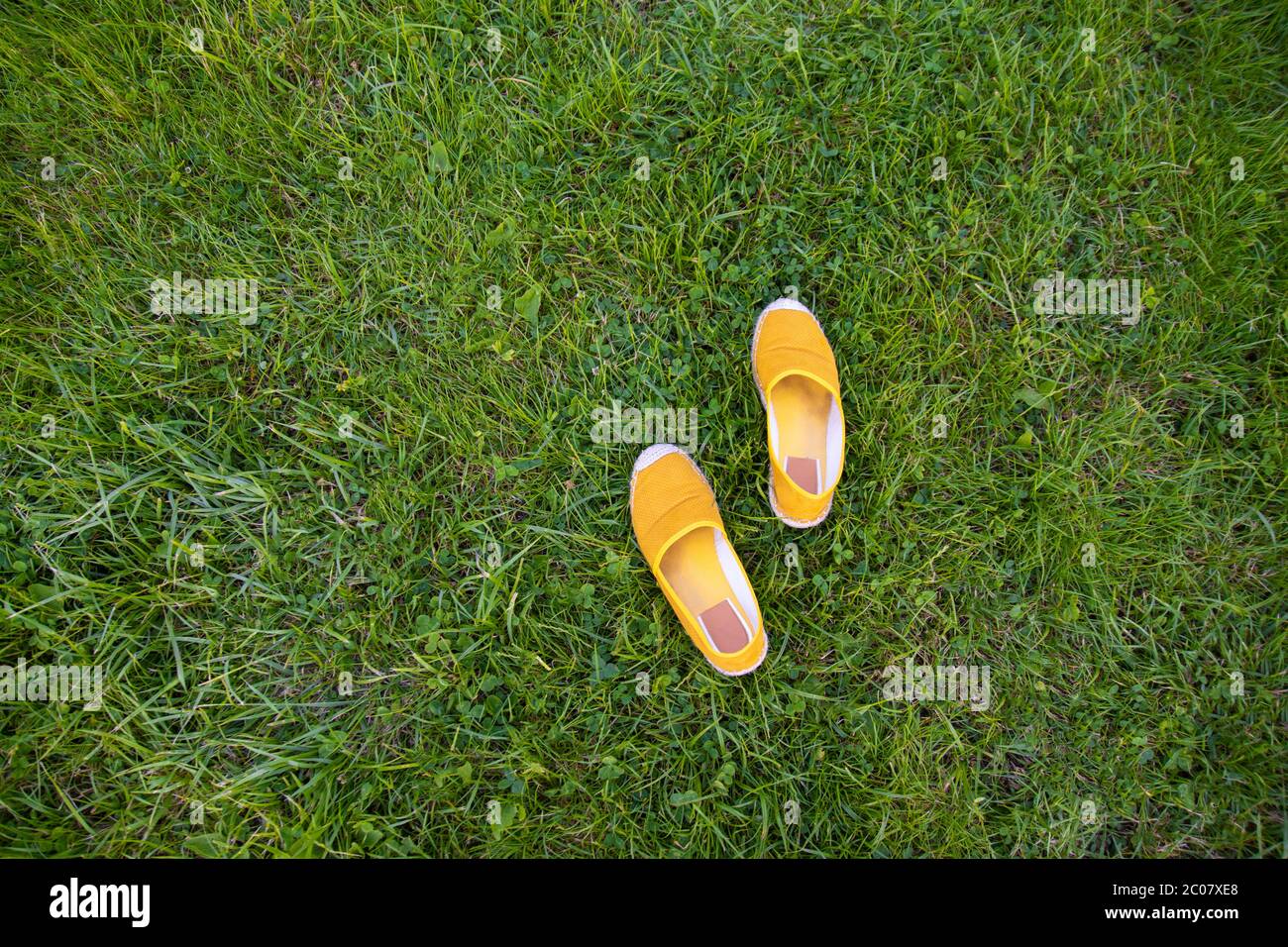 Yellow summer shoes on green grass. View above. Copy space. Stock Photo