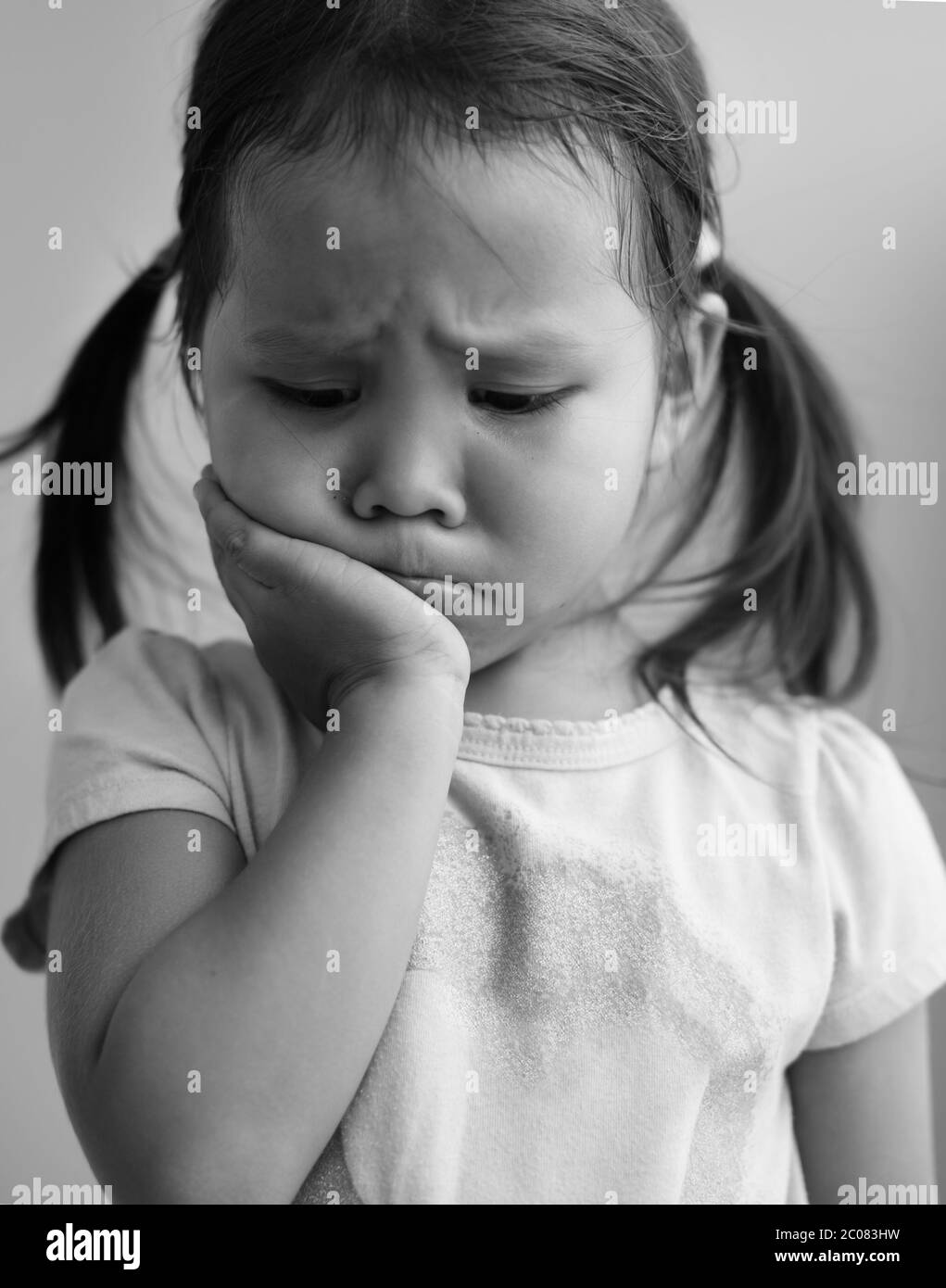 A portrait of a sad little girl crying and afraid in black and ...