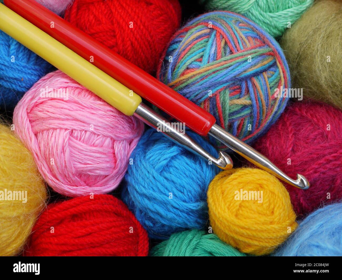 colorful balls of wool with crochet hooks Stock Photo