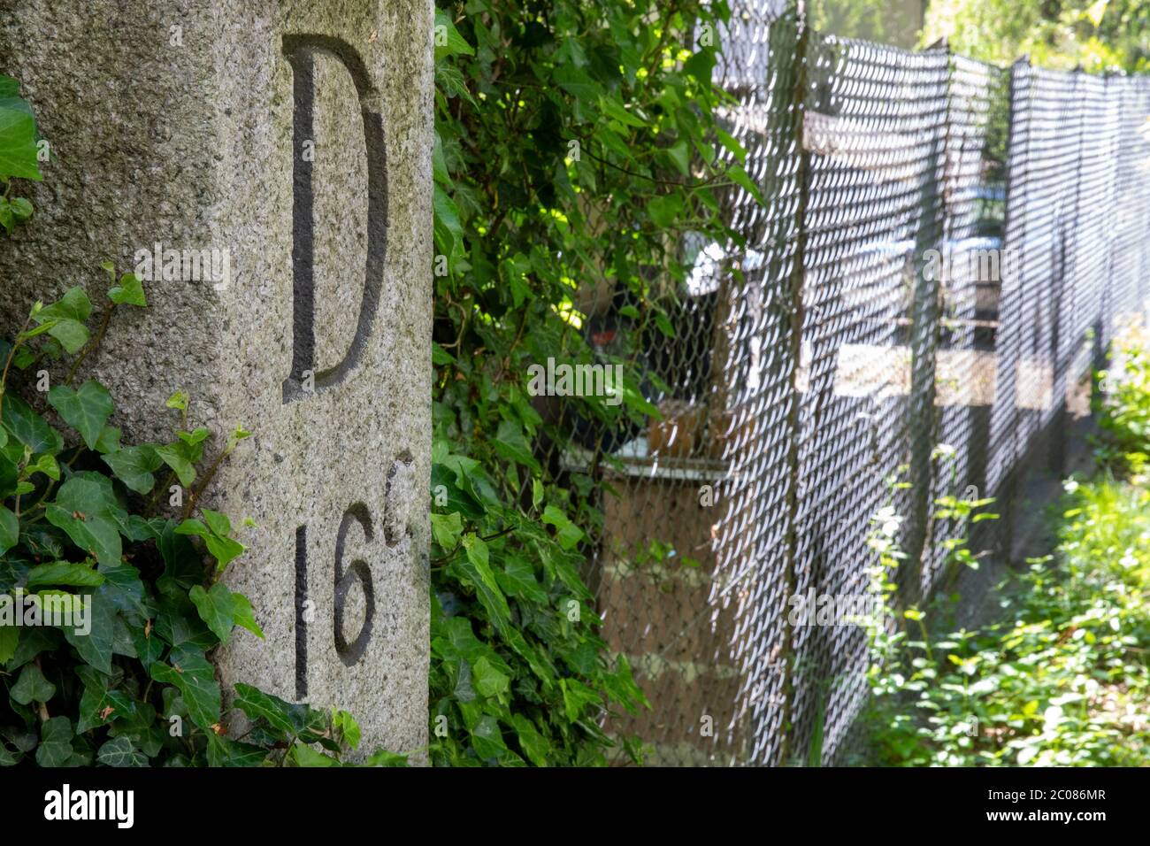 Wegen der Ausbreitung des Corona-Virus haben die Schweiz und Deutschland ihre Grenzen geschlossen. Alter Hintergarten-Grenzzaun mit Grenzstein D16C. K Stock Photo