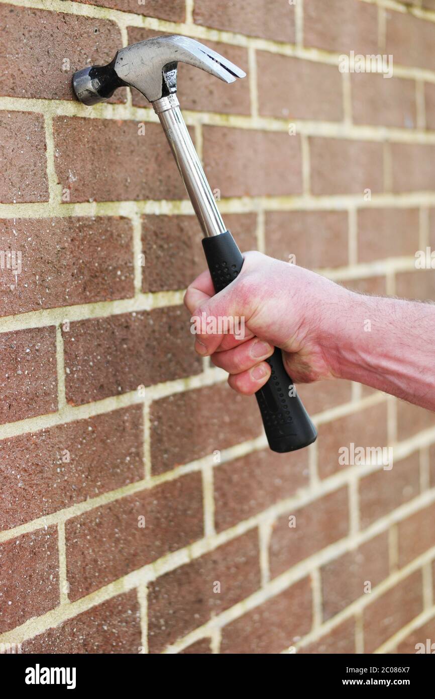 Man hitting a brick wall with a hammer Stock Photo