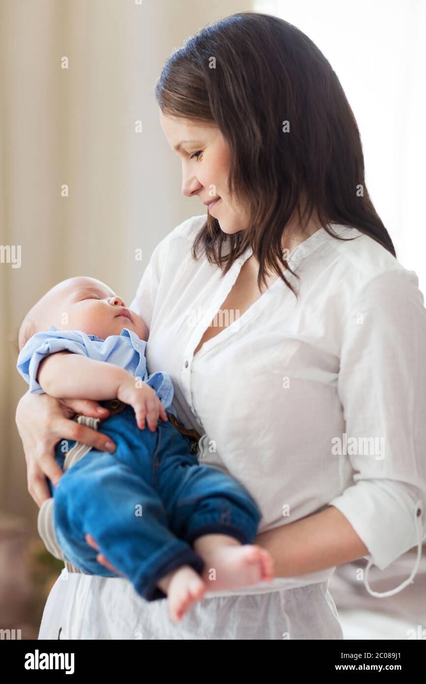 Baby falling asleep in the arms of her mother Stock Photo Alamy