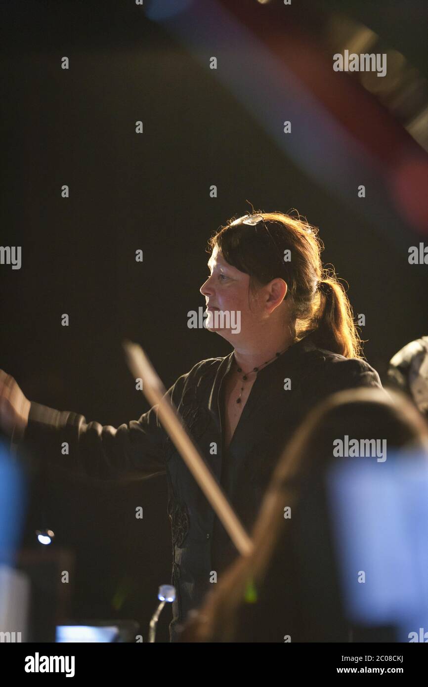 Female conductor (model released) leads orchestra in concert Stock Photo