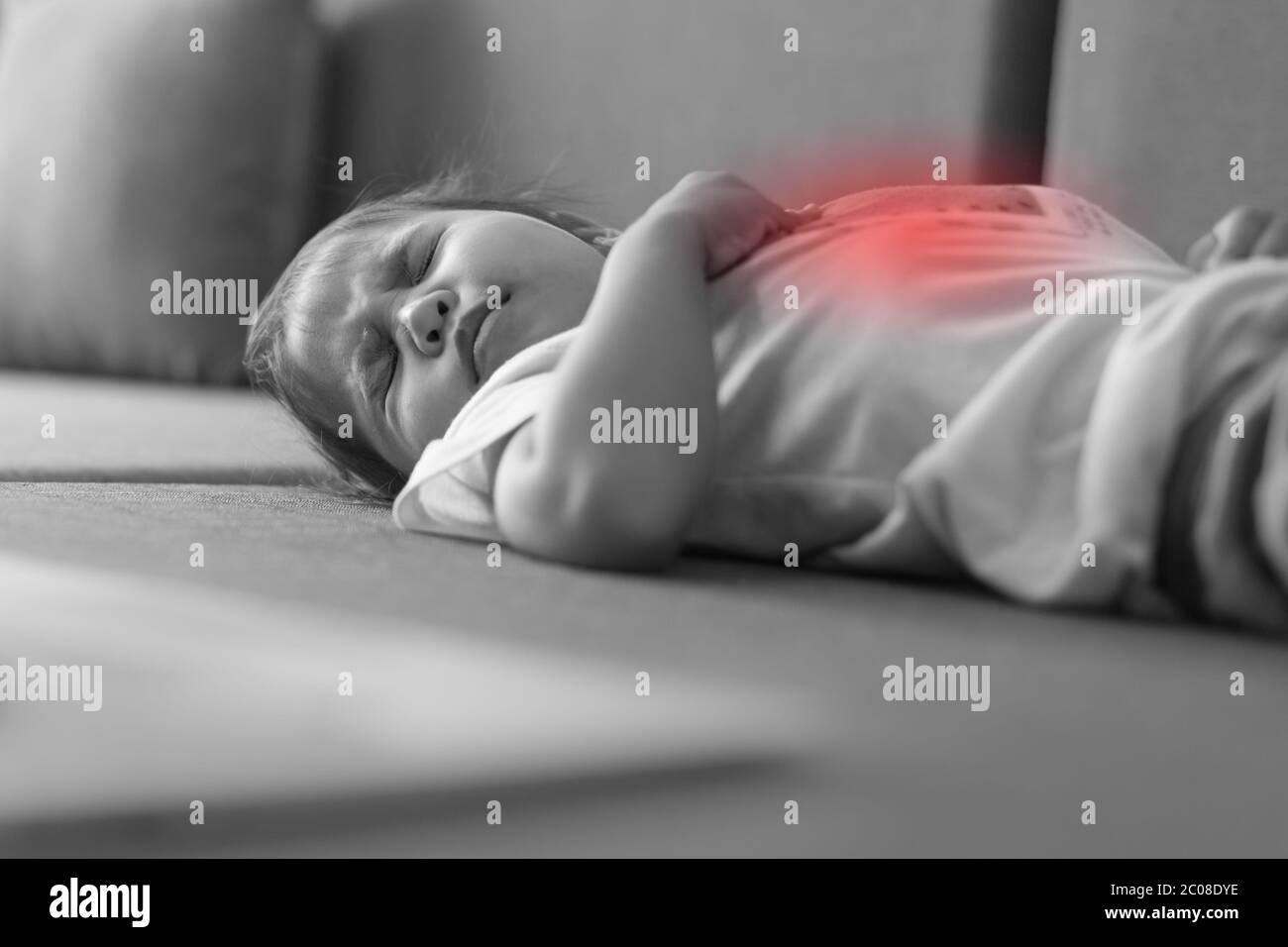 A small toddler lying on the bed sick, crying from her stomach hurting