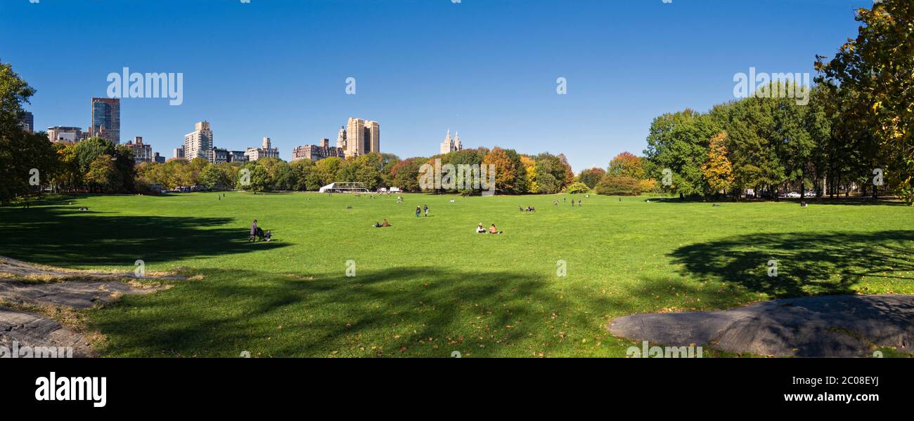 People enjoy Sheep Meadow in Central Park looking towards upper west side of Manhattan. Stock Photo