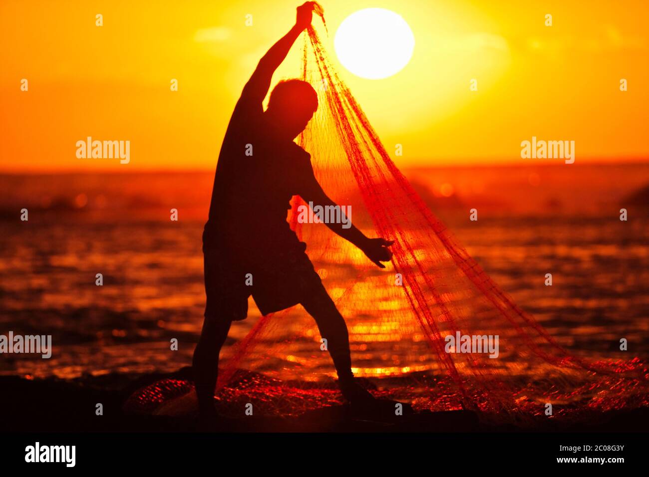 Hawaiian Fisherman (model released) hauls in his fishing net at sunset in Keauhou, Hawaii Stock Photo
