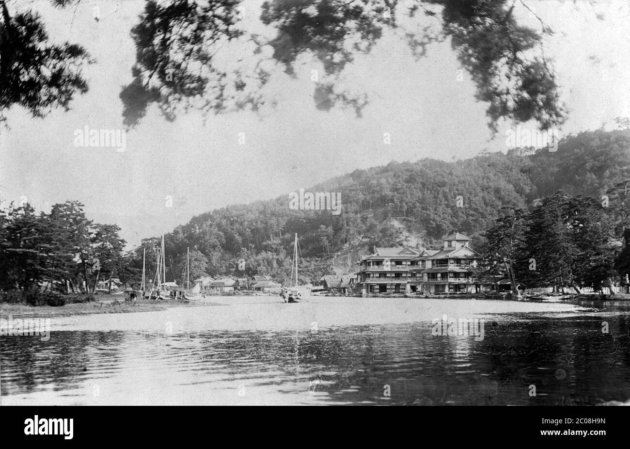 [ 1900s Japan - Miyazu, Kyoto ] — Monju Hotel in Miyazu, Kyoto Prefecture, early 1900s.  The trees on the protruding bit of land on the left are part of Amanohashidate, considered to be one of Japan's three most beautiful sights.  Hidden behind the trees on the right is the entrance gate of Chionji Temple.  In 1923 (Taisho 12) the Kaisenbashi bridge was built at this spot to connect Amanohashidate with the mainland.  20th century vintage gelatin silver print. Stock Photo
