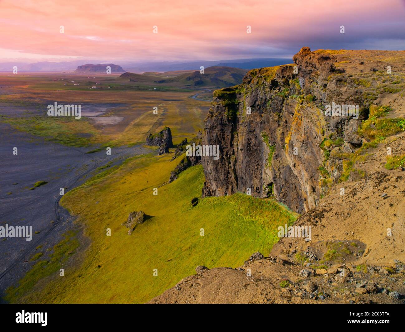 Dramatic rocky coastline landscape with green steep slopes, wild rocks and black beach, Iceland Stock Photo