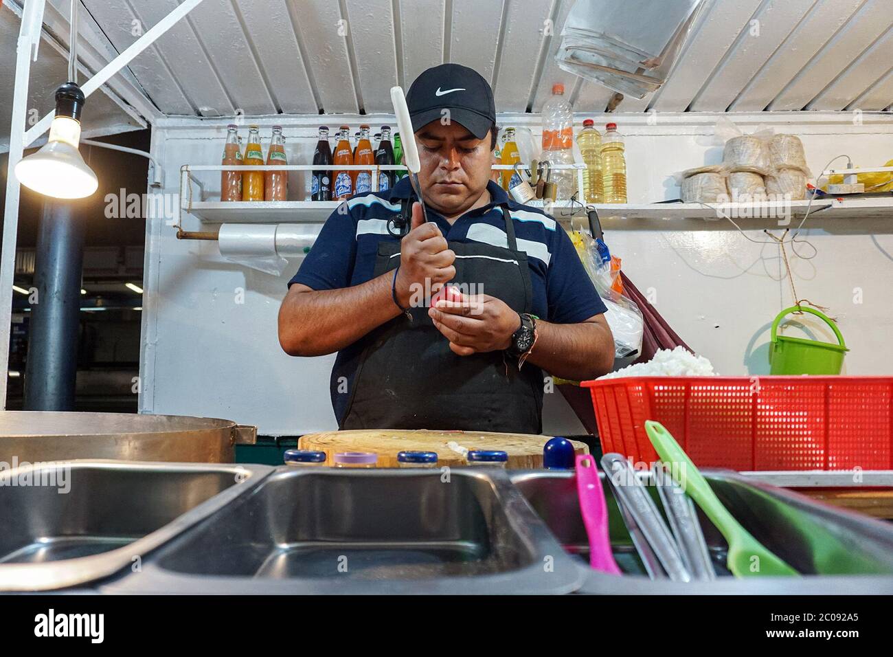 Miguel Ángel Xochicale chops vegetables for salsa early in the morning at a taco stand in Colonia Albert, Mexico City. The taco stand is open 24 hours a day and is located outside the Portales metro stop, which keeps customers coming at all hours. (Mayela Sánchez, GPJ Mexico) Stock Photo