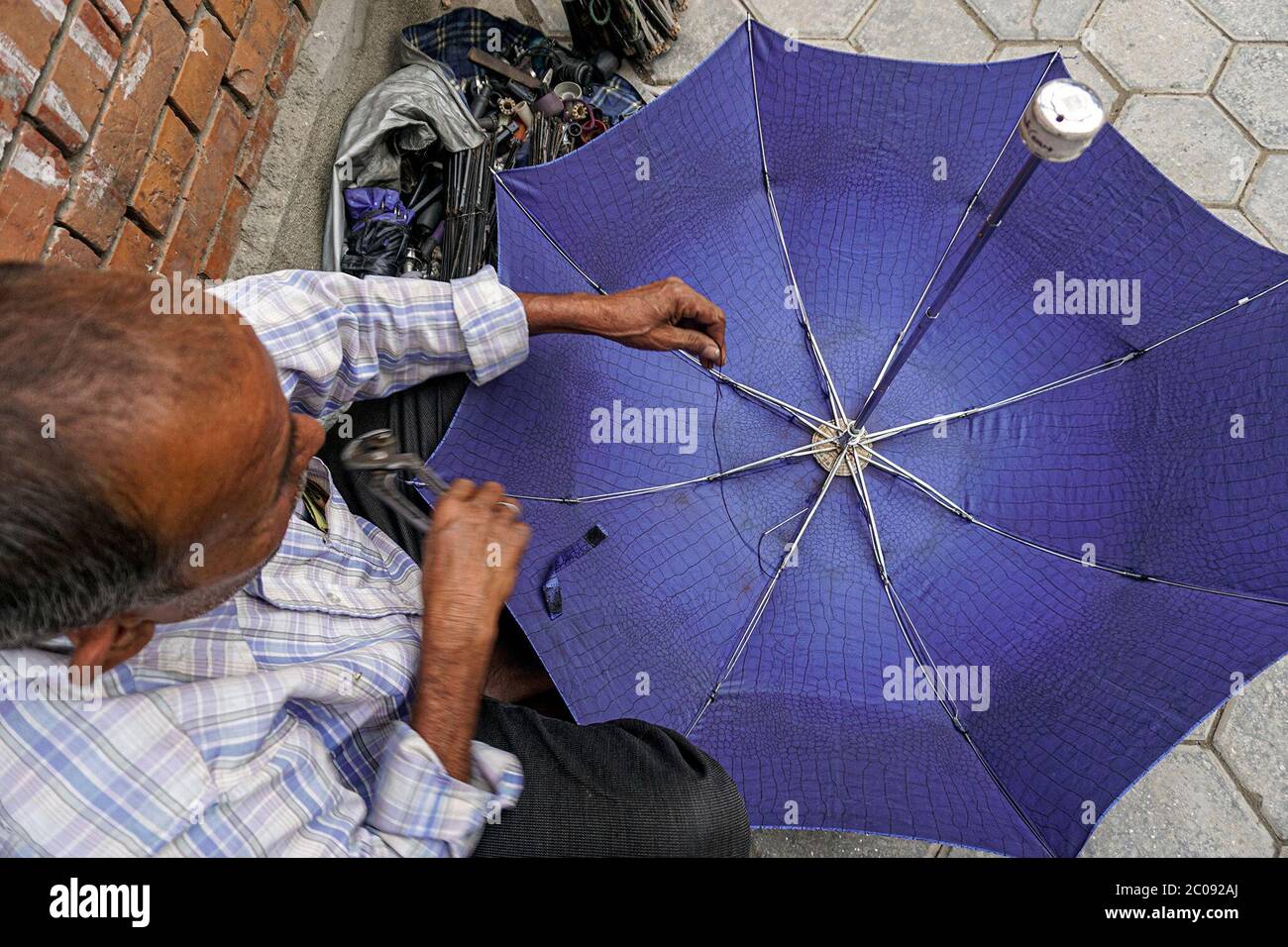 Mohammad Sainula repairs an umbrella in Kathmandu, Nepal. Sainula repairs umbrellas during