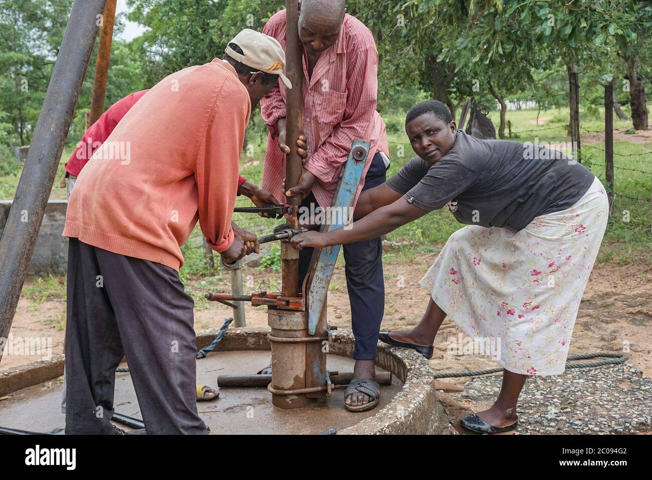 Primrose Masiyakurima (right) and other community members repair a broken borehole in Dora Ward 35, located in Zimbabwe’s Mutare District. This borehole provides water to 22 households and a school of 350 children. A few villagers are given equipment and trained as Village Pump Mechanics (VPMs), so they can repair broken boreholes themselves instead of waiting for district authorities. (Evidence Chenjerai, GPJ Zimbabwe) Stock Photo