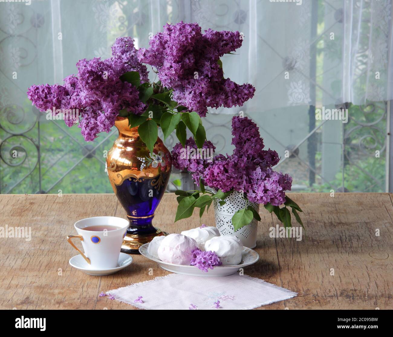 Tea in a porcelain cup, a zephyr and a lilac bouqu Stock Photo