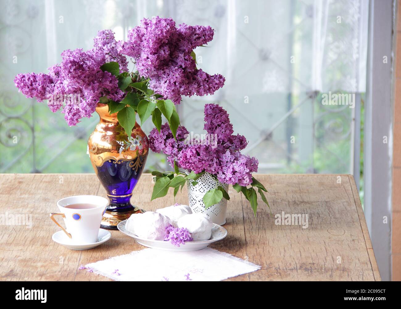 Tea in a porcelain cup, a zephyr and a lilac bouqu Stock Photo
