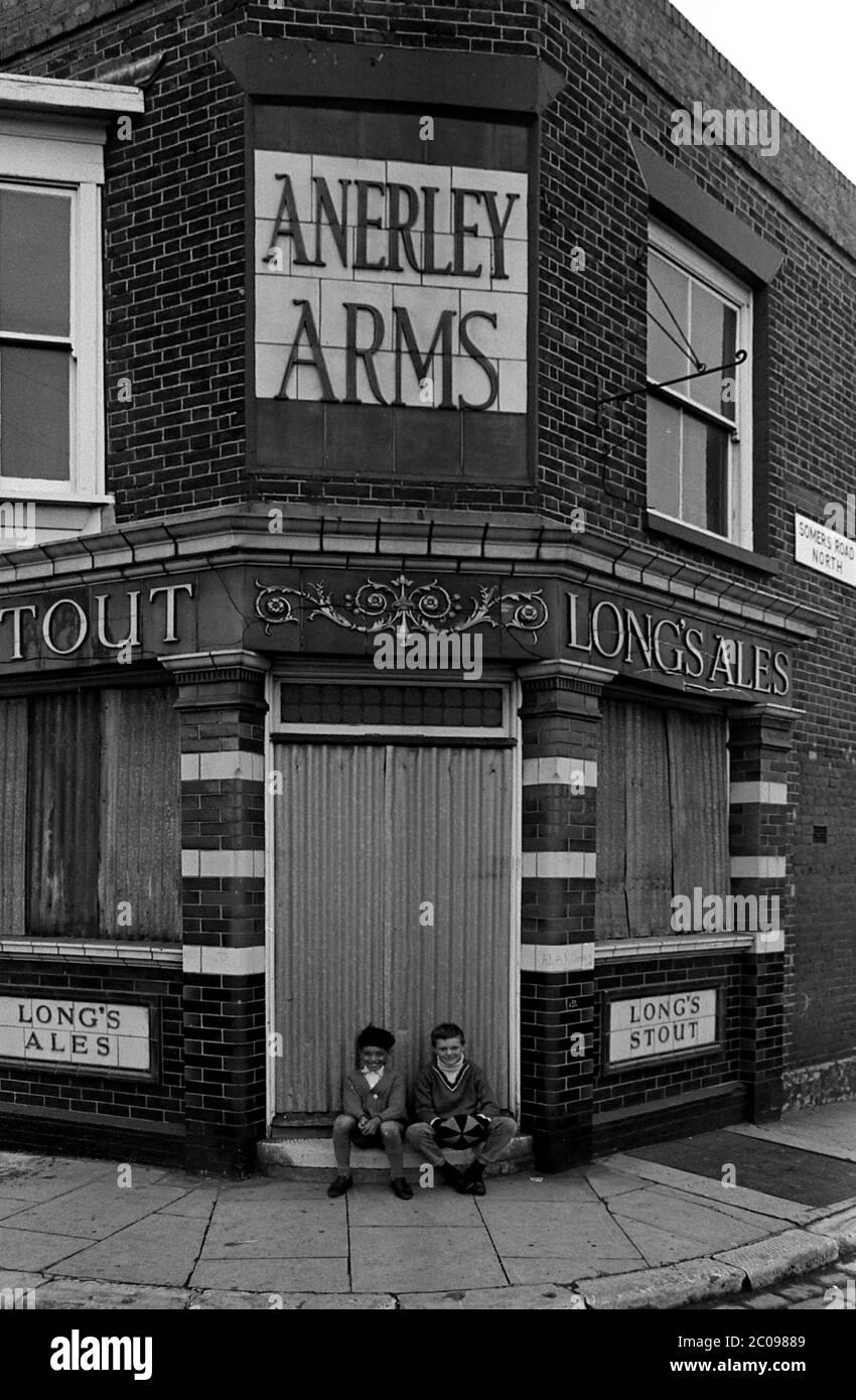 AJAXNETPHOTO. 14TH SEPTEMBER, 1969. PORTSMOUTH, ENGLAND. - LOST PUBS - TWO YOUNGSTERS SAT ON THE DOORSTEP OF THE BOARDED UP ANERLEY ARMS PUBLIC HOUSE CORNER OF SOMERS ROAD NORTH.PHOTO:JONATHAN EASTLAND/AJAX REF:356947 9 103 Stock Photo