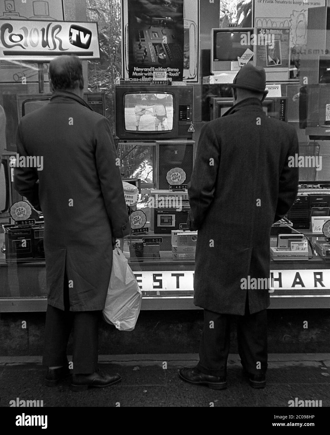 AJAXNETPHOTO. 1977. PORTSMOUTH, ENGLAND. - WINDOW SHOPPING - TWO MEN LOOKING AT DISPLAY OF GOODS IN WINDOW OF ELECTRICAL RETAILER IN LONDON ROAD NORTH END WHEN PRICE OF A COLOUR TELEVISION WAS £259.00 AND RADIO CASSETTE RECORDER £48.50.   PHOTO:JONATHAN EASTLAND/AJAX REF:35773A36 Stock Photo