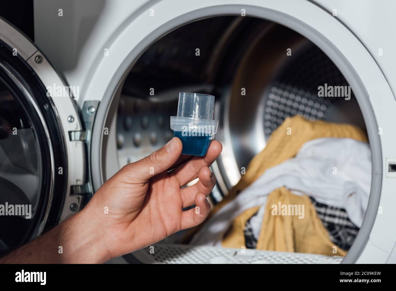 Closeup of liquid gel detergent pouring from the spout of a plastic bottle  into a measuring cup, with dirty washing / laundry in the background Stock  Photo - Alamy