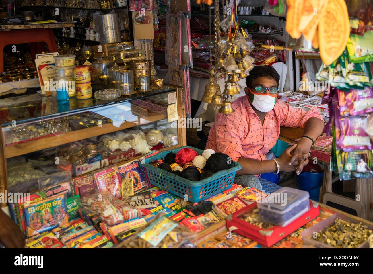 An Indian shopkeeper sells votive threads, coconuts and flower garlands which will be offered by Hindu devotees to the Hindu deities inside  Mandir (T Stock Photo