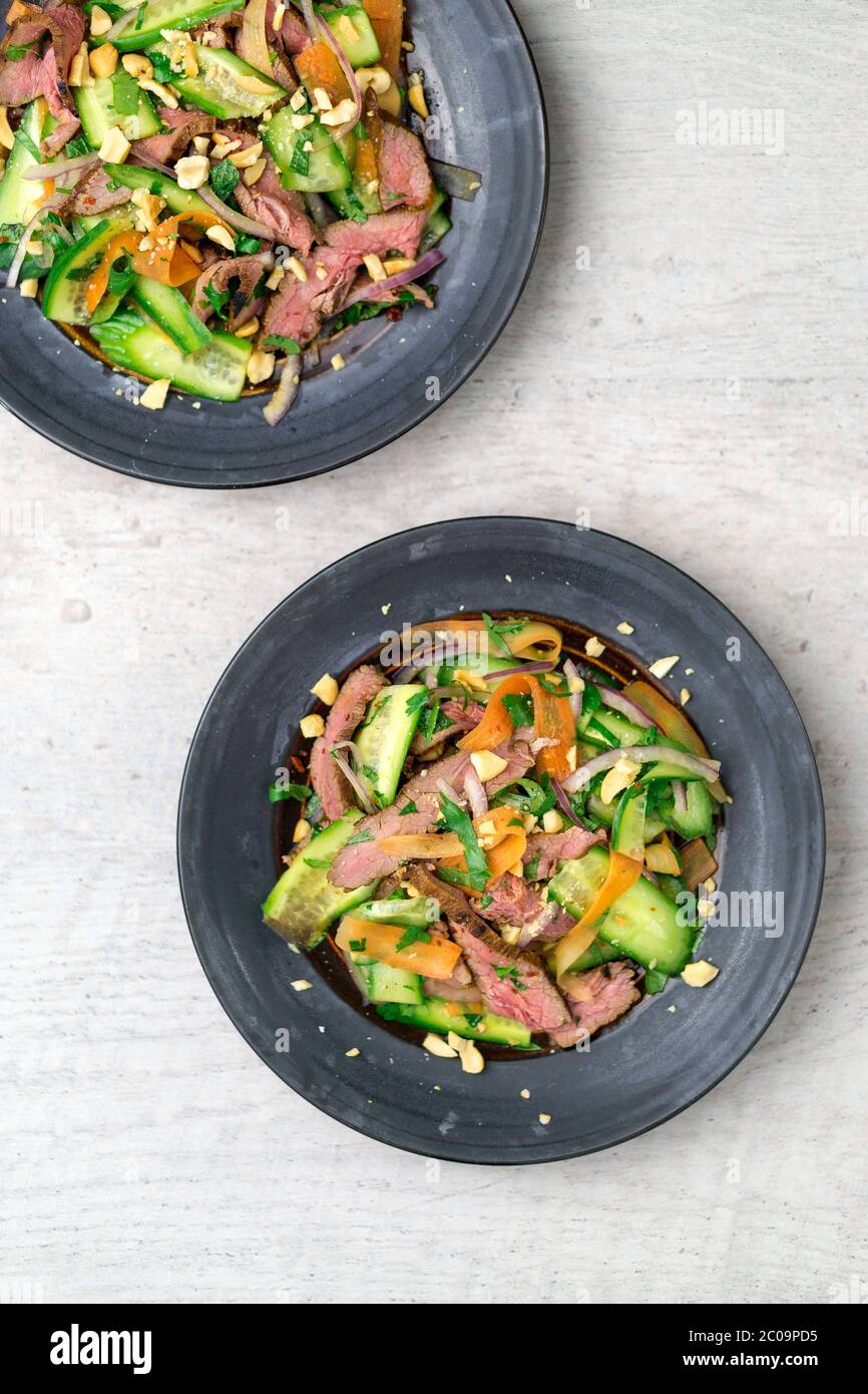 Flat top view of 2 plates of asian beef salad. Inspired by Thai & Vietnamese cuisine, this salad is made with fresh healthy vegetables. Stock Photo
