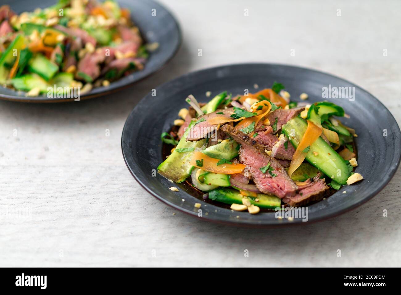 Angled view of 2 plates of asian beef salad. Inspired by Thai and Vietnamese cuisine, this salad is made with fresh healthy vegetables. Stock Photo