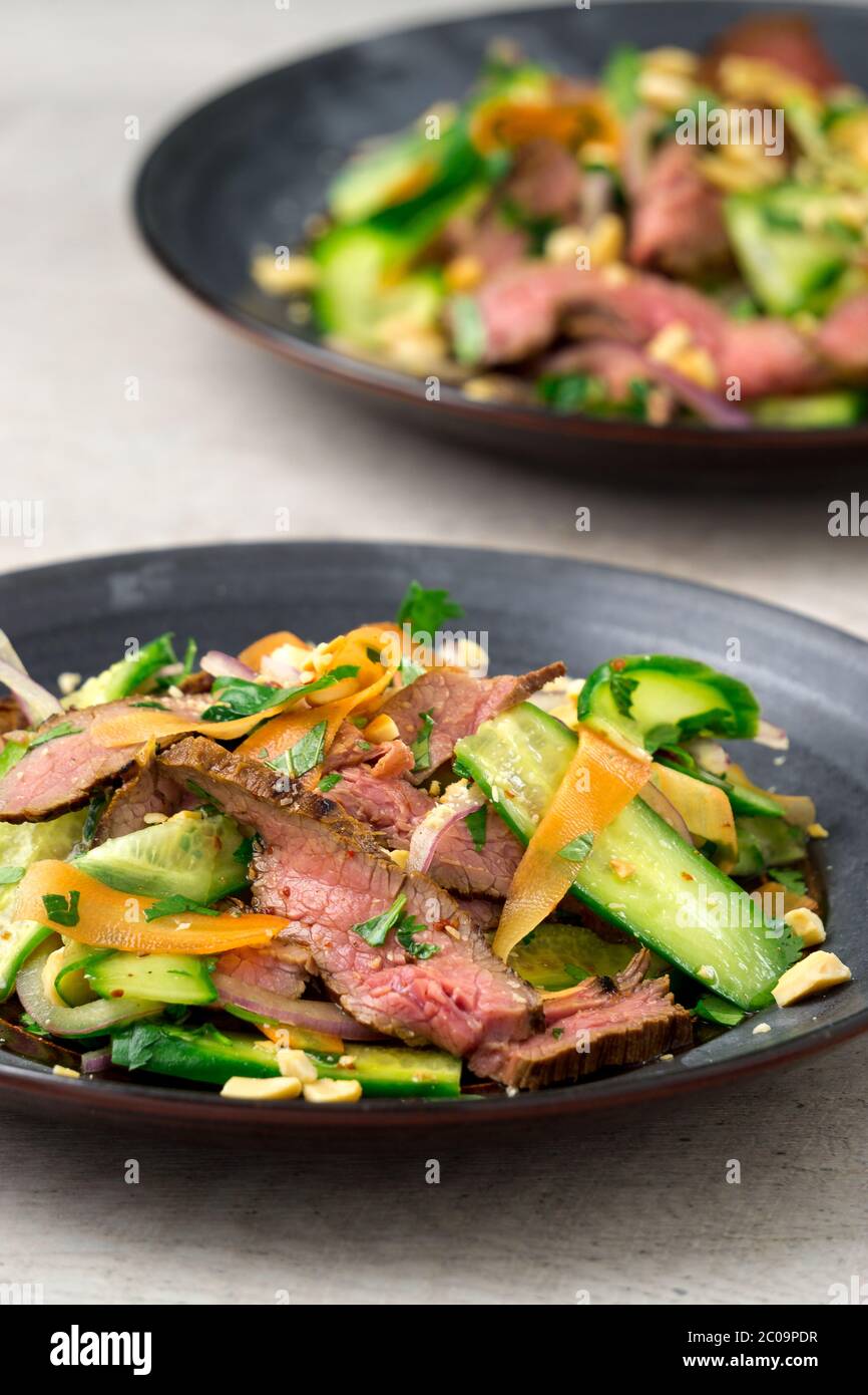 Vertical view of 2 plates of asian beef salad. Inspired by Thai and Vietnamese salads, packed with fresh healthy vegetables. Stock Photo