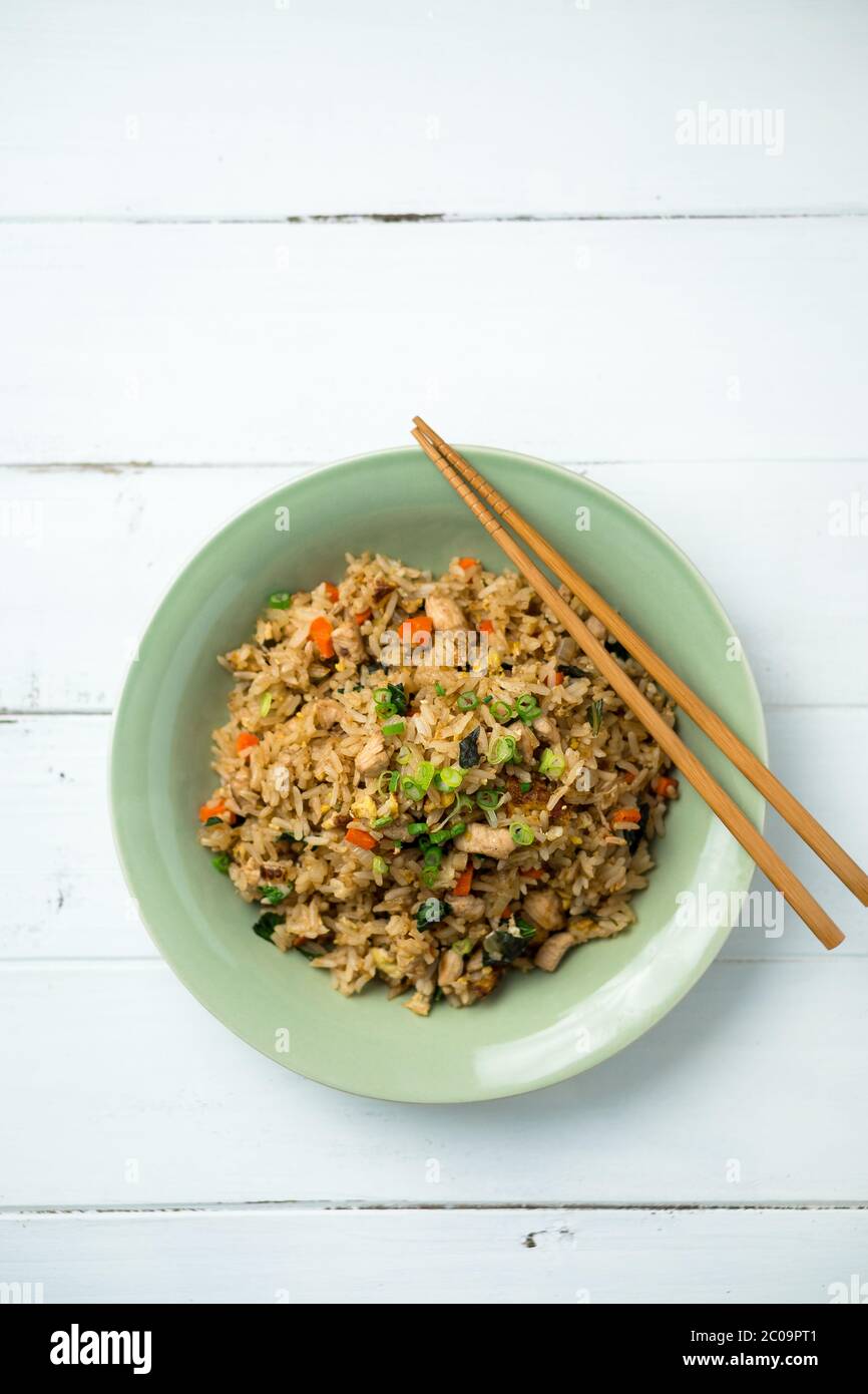 Basil chicken fried rice with chopsticks on a white wooden background viewed from above. This thai inspired meal is perfect for a lunch or side dish. Stock Photo