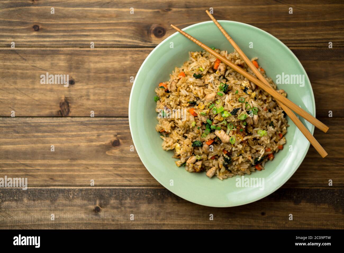 Basil chicken fried rice with chopsticks on a wooden background viewed from above. This thai inspired meal is perfect for a lunch or side dish. Stock Photo