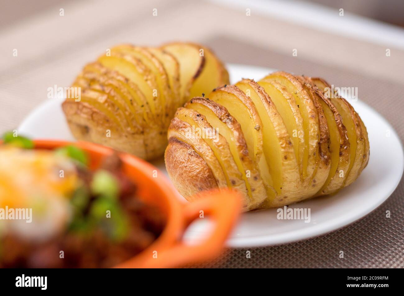 Side dish of oven baked & roasted hasselback potatoes. Hasselback potatoes are thinly sliced wedges of potatoes that are still joined at the bottom an Stock Photo