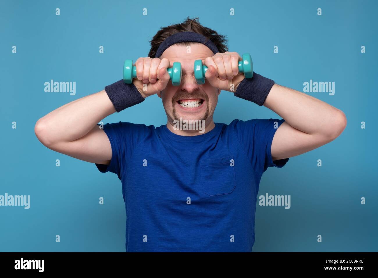 Athletic funny young man doing exercise dumbbell Stock Photo