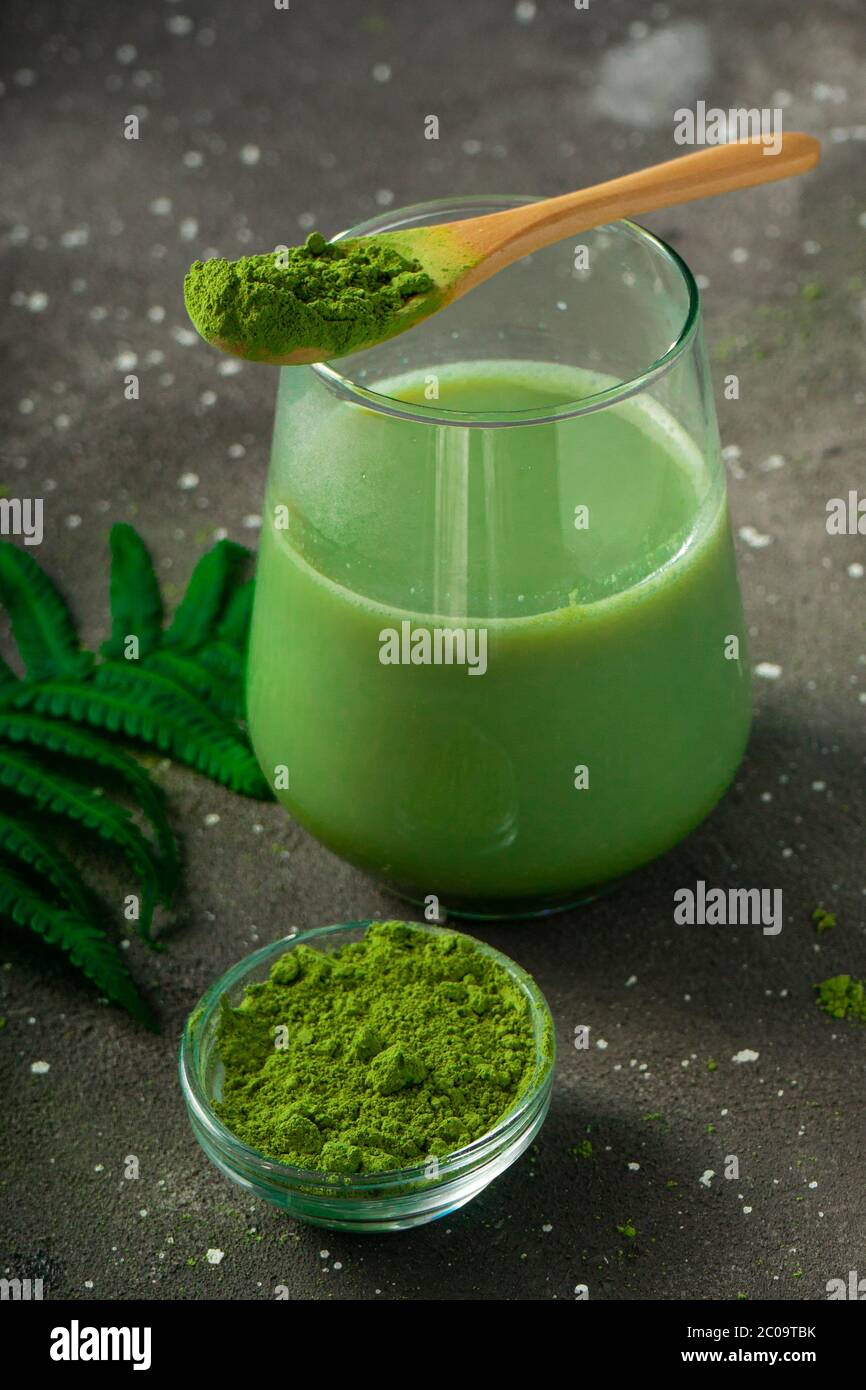 selective focus, Japanese green matcha tea with milk, with a wooden spoon and foliage on a dark background Stock Photo